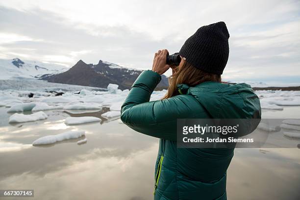 a female looking at a glacier. - looking through binoculars stock pictures, royalty-free photos & images