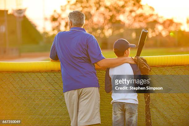 father and son watching a baseball game - baseball kid stock-fotos und bilder