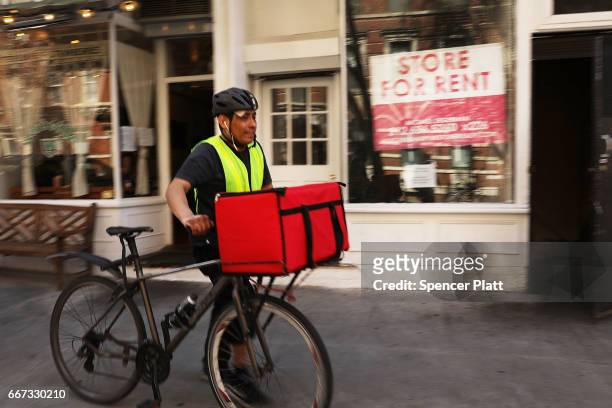Delivery man walks by empty store fronts in a trendy West Village neighborhood on April 11, 2017 in New York City. Many residents and tourists alike...