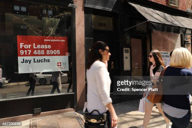 People walk by empty store fronts in a trendy West Village neighborhood on April 11, 2017 in New York City. Many residents and tourists alike are...