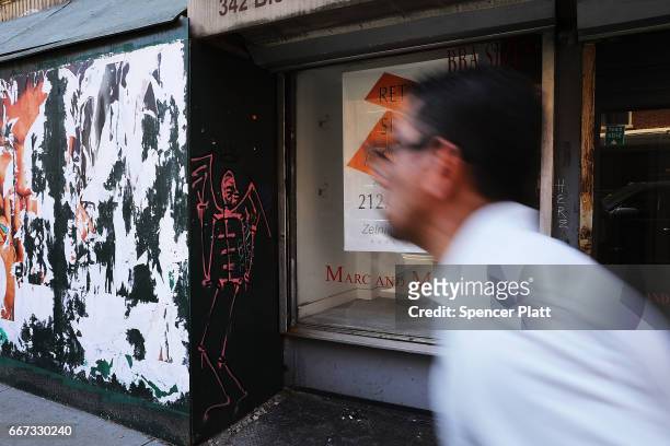 People walk by empty store fronts in a trendy West Village neighborhood on April 11, 2017 in New York City. Many residents and tourists alike are...