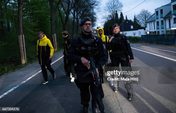 Sven Bender, Marcel Schmelzer and Nuri Sahin of Borussia Dortmund are escorted to a car by police after the team bus of the Borussia Dortmund was...