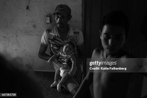 Alexandre Santiago holds his son, Samuel Amorim, who was born with microcephaly, in their home in one of Campina Grande's poorest neighborhoods....