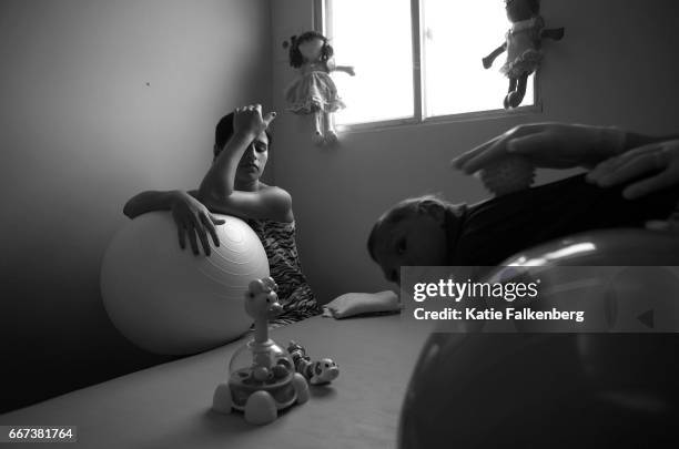 Kalissandra de Olivera, age 17, rests on an exercise ball as her son, Nicolas Felipe Alves de Olivera, 3 months, receives physiotherapy at Pedro 1...