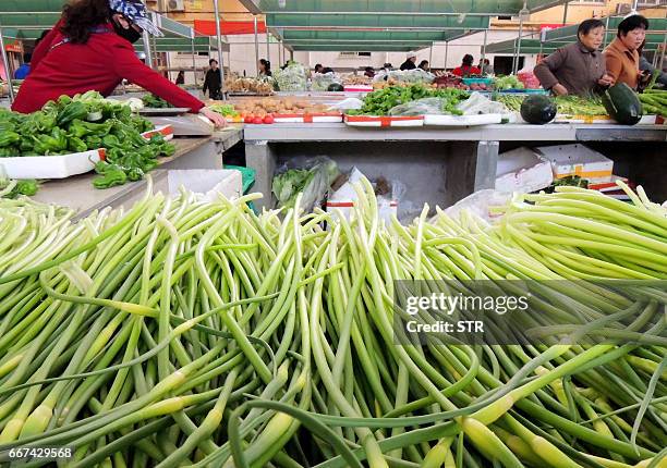 Customers select vegetables at a market in Lianyungang, east China's Jiangsu province on April 12, 2017. Prices for goods at the factory gate in...