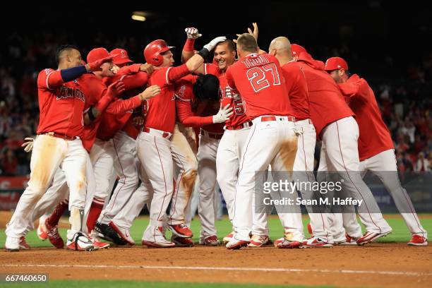 Carlos Perez of the Los Angeles Angels of Anaheim is swarmed by teammates after hitting game winning RBI bunt during the tenth inning of a game...