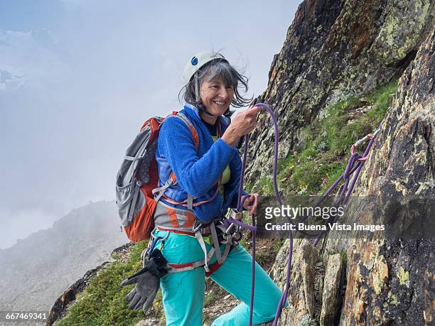 senior woman climbing a mountain - rocky mountaineer stock pictures, royalty-free photos & images