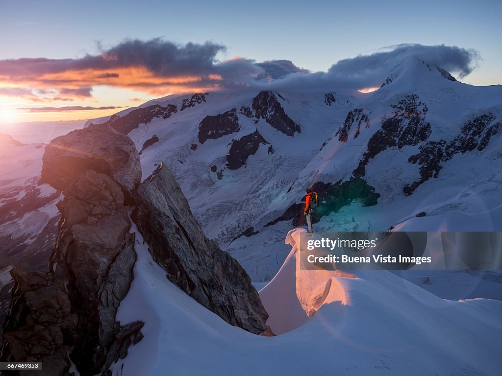 Climber on a peak watching sunrise