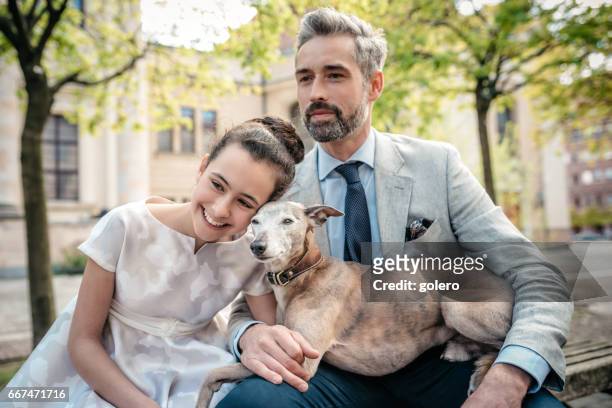 elegant father sitting on bench with well dressed daughter and dog - elegance family stock pictures, royalty-free photos & images