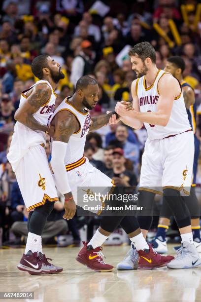Kyrie Irving and Kevin Love of the Cleveland Cavaliers help LeBron James of the Cleveland Cavaliers to his feet after James was fouled during the...