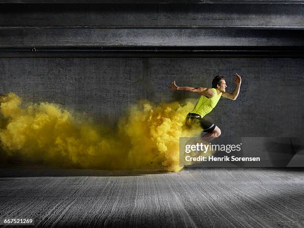 male athlete running through smoke - add value stock-fotos und bilder