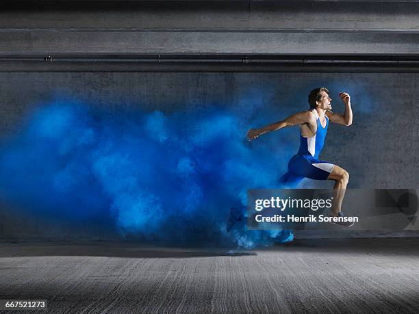 male athlete leaping through smoke - blue shoe stock-fotos und bilder