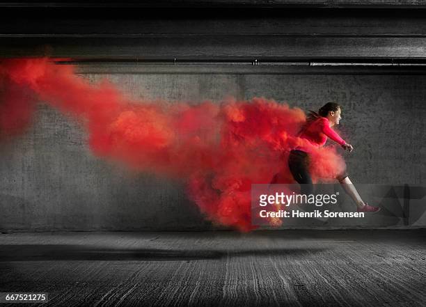 female athlete leaping through smoke - velocità foto e immagini stock