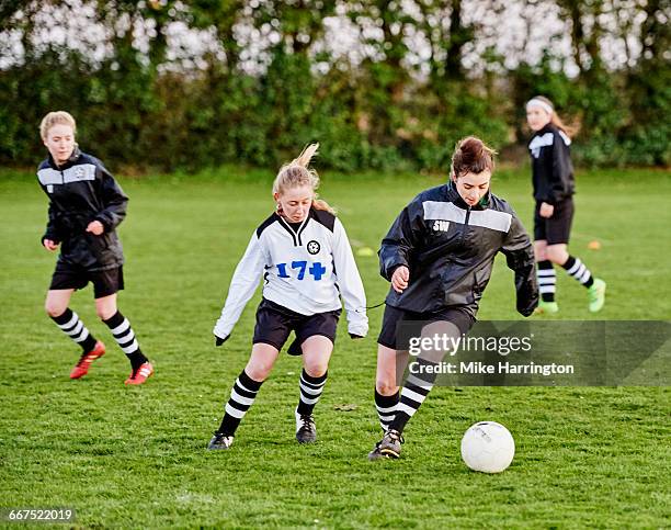 young female footballer about to tackle opponent - obstruir - fotografias e filmes do acervo