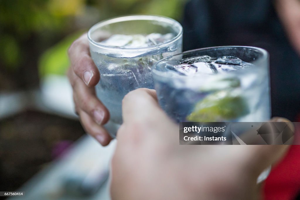 Concept de célébration avec main gros plan d’un couple célébrant le début de leurs vacances avec chacun un gin & tonique.