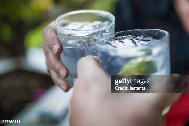 celebration concept with hand close-up of a couple celebrating the beginning of their vacations with each a gin & tonic. - gin and tonic stock pictures, royalty-free photos & images