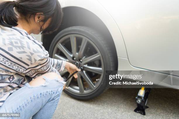 young women changing a flat tire - car jack stock pictures, royalty-free photos & images