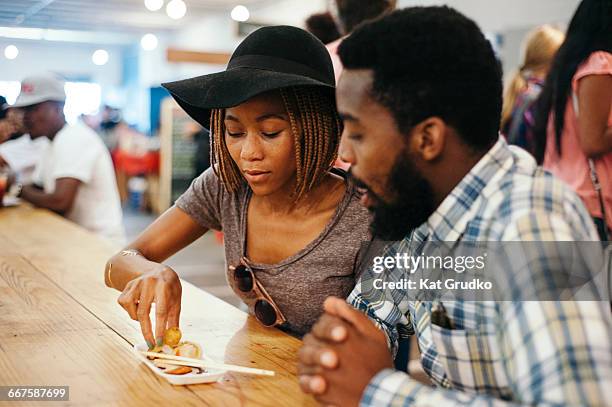 young trendy ethnic african couple eating chinese food in trendy market in braamfontein johannesburg south africa - curly arrow stock pictures, royalty-free photos & images