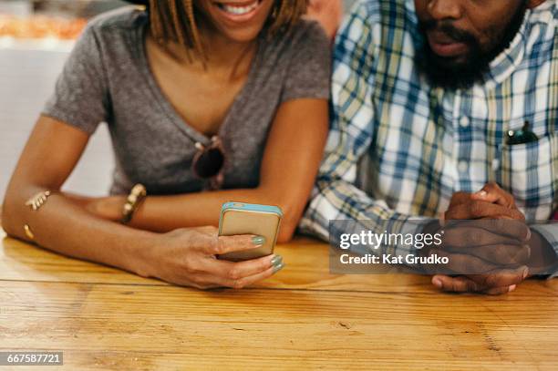 young ethnic african couple looking at mobile device in trendy market in braamfontein johannesburg south africa - curly arrow stock pictures, royalty-free photos & images