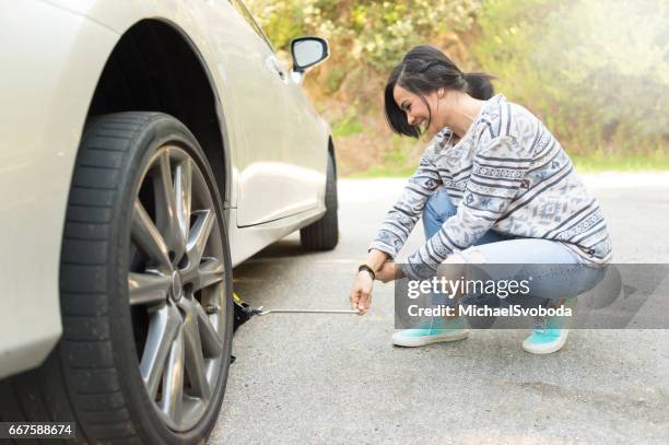 junge frauen, die einen platten reifen ändern - car jack stock-fotos und bilder