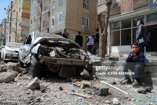 People gather near the site of an explosion that hit the police headquarters the day before in the Kurdish majority city of Diyarbakir, southeastern...