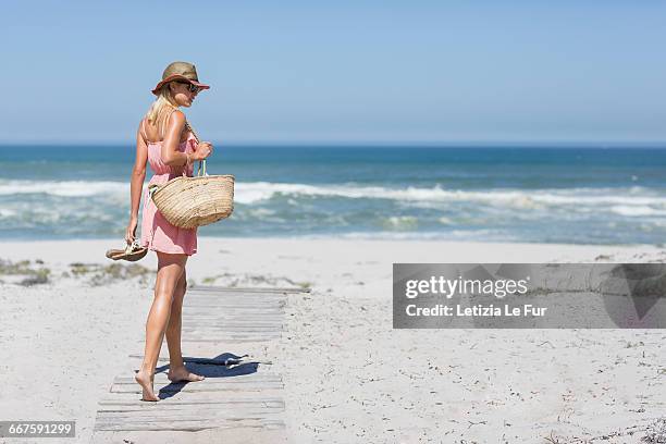 young woman walking on the beach - beach bag foto e immagini stock