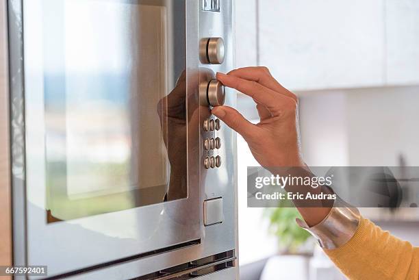 close-up of a woman hand using an oven - microwave oven stockfoto's en -beelden