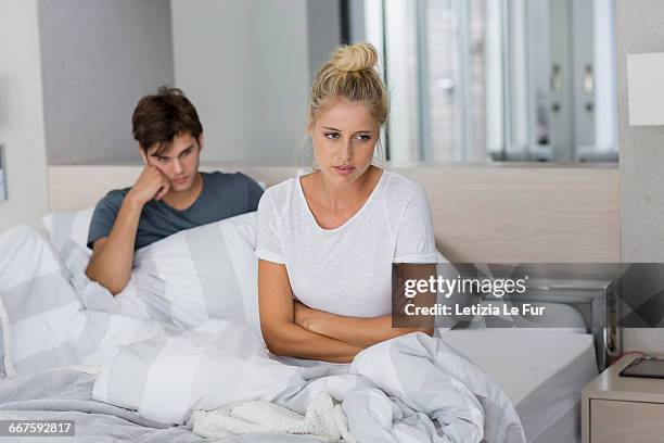 couple sitting on the bed with relationship difficulties - boyfriend stockfoto's en -beelden