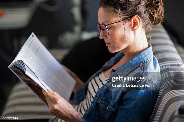 close-up of a beautiful woman reading a magazine - revistas fotografías e imágenes de stock