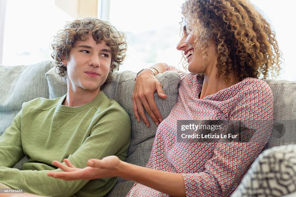 Happy mother and son talking on couch in living room