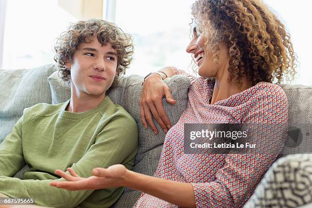 happy mother and son talking on couch in living room - mother son stock pictures, royalty-free photos & images