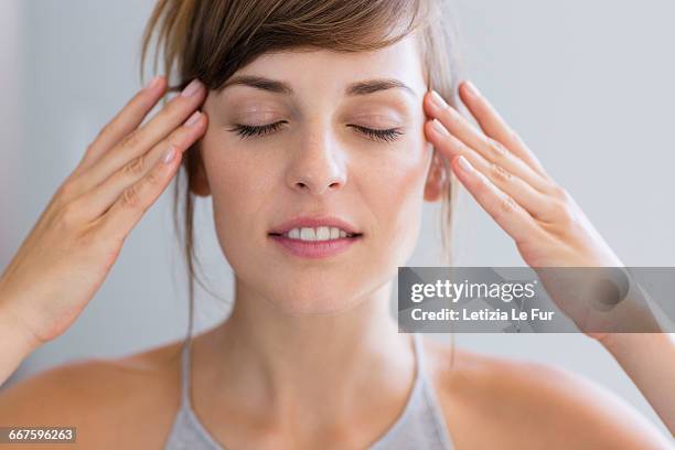 woman touching temples with fingers - forehead stock pictures, royalty-free photos & images