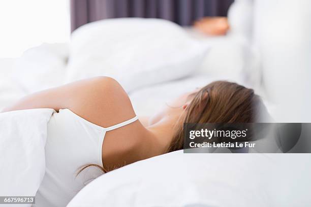 rear view of a woman resting on the bed - lying on side stock-fotos und bilder