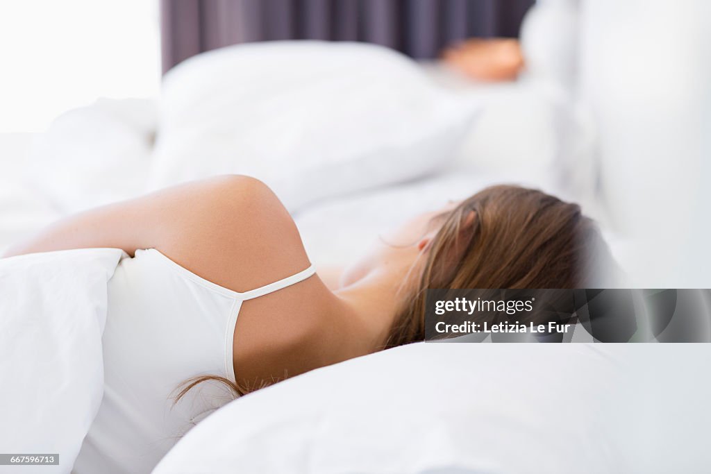 Rear view of a woman resting on the bed