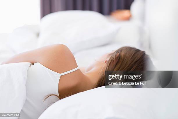 rear view of a woman resting on the bed - acostado de lado fotografías e imágenes de stock