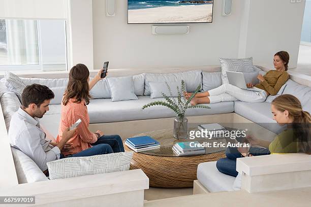 family in living room busy in different activities - touchpad stock pictures, royalty-free photos & images