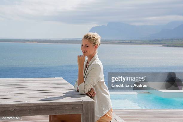 beautiful woman sitting on bench at lakeshore - pool table stock-fotos und bilder