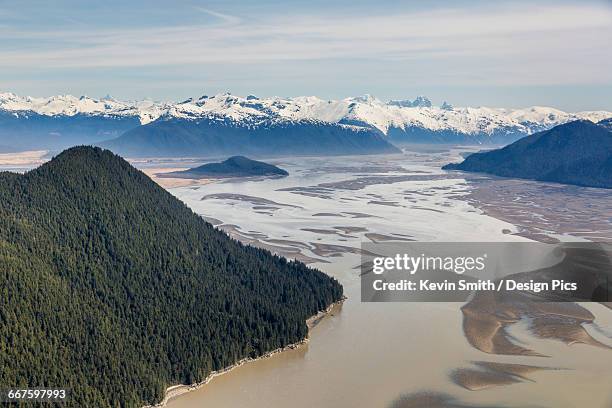 aerial view of woronkofski island along the stikine river delta, low tide revealing mud flats below the snow capped peaks in the background - stikine river stock pictures, royalty-free photos & images
