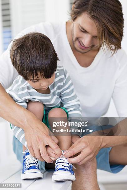 father tying sons shoelaces at home - letizia shoe detail imagens e fotografias de stock