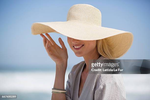 happy young woman wearing sunhat on beach - hats ストックフォトと画像