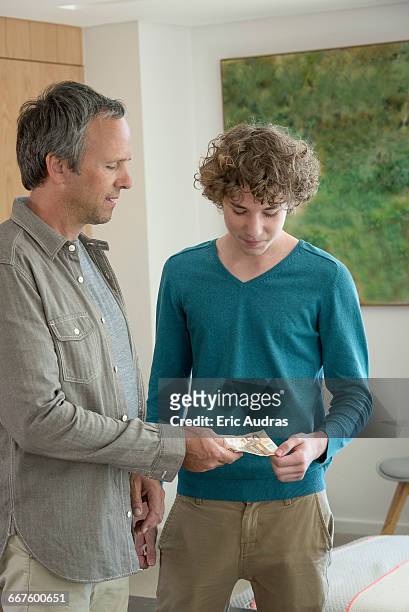 father giving teenage son pocket money - boys money stock pictures, royalty-free photos & images