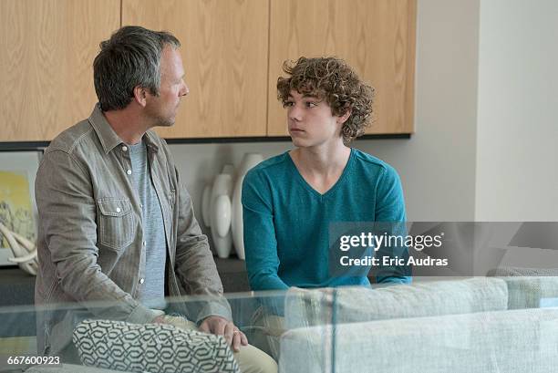 father and son having serious discussion in a living room - serious teenager boy imagens e fotografias de stock