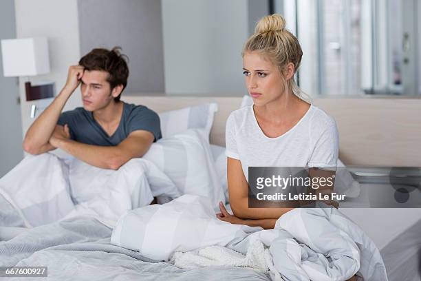 young couple sitting on the bed with relationship difficulties - couple relationship difficulties stock pictures, royalty-free photos & images