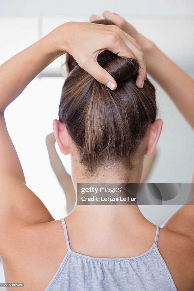 Beautiful young woman adjusting her hair in a bathroom