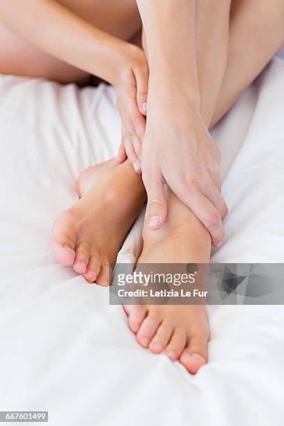 low section view of a woman sitting on the bed - foot massage stock-fotos und bilder