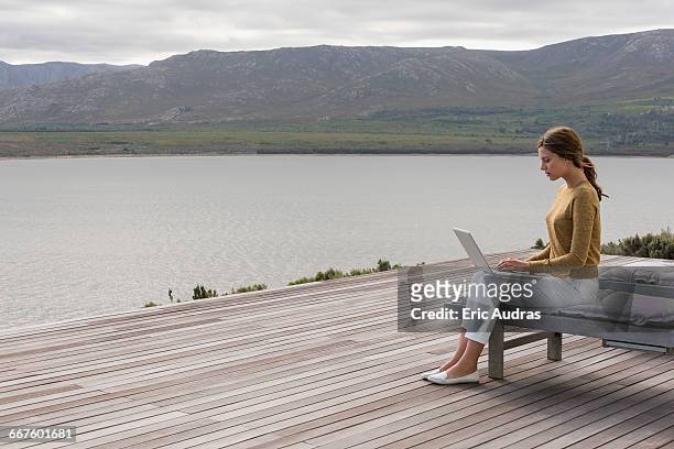 side profile of a beautiful woman using a laptop - profile laptop sitting stock pictures, royalty-free photos & images