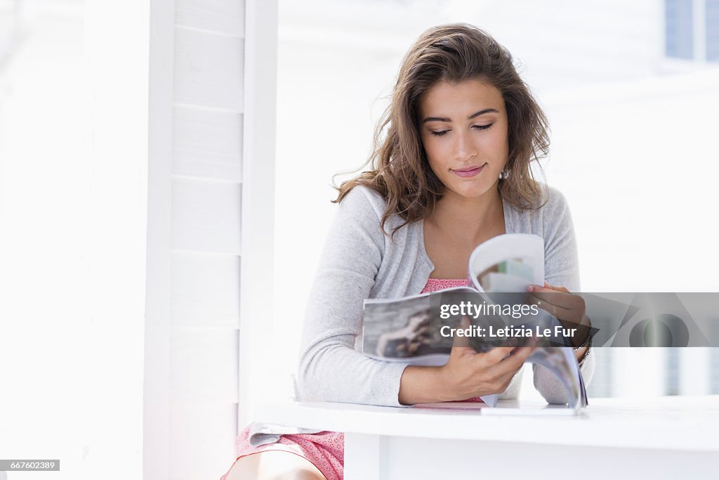 Young woman reading magazine at home