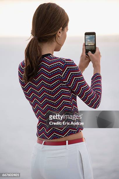 beautiful young woman taking picture with camera phone at riverbank - tre quarti foto e immagini stock