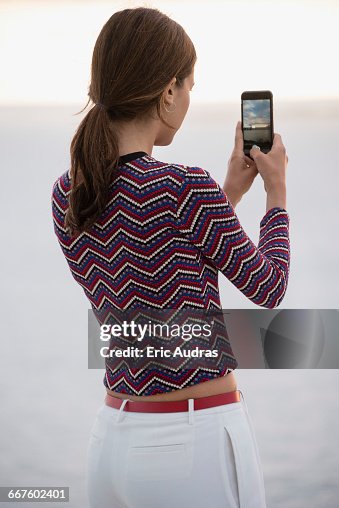 Beautiful young woman taking picture with camera phone at riverbank Beautiful young woman taking picture with camera phone at riverbank