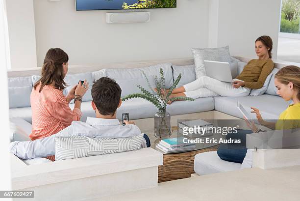 family in living room busy in different activities - touchpad stockfoto's en -beelden
